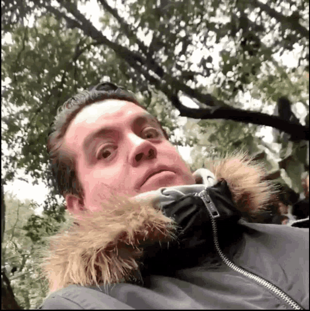a man wearing a jacket with a fur hood is looking at the camera