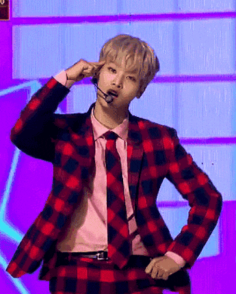 a man in a plaid suit and tie is holding his finger to his ear