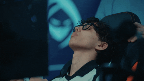 a man wearing glasses is sitting in a chair with his head down
