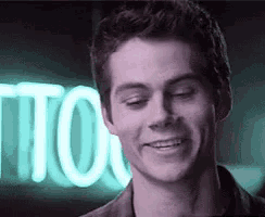 a man is smiling in front of a neon sign that says tito .