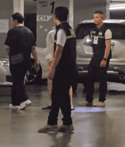 a group of people are walking in a parking garage with a sign that says c19 on it