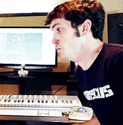 a man wearing a shirt that says ' jesus ' on it sits in front of a keyboard