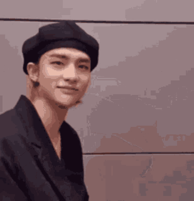 a young man wearing a black beret and a black shirt is smiling .