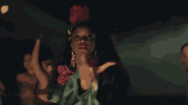 a woman in a green dress is dancing in front of a group of people in a dark room .