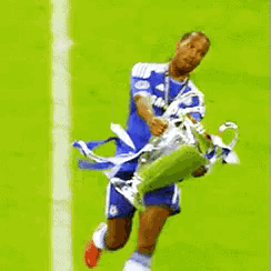 a soccer player holding a trophy on a green field