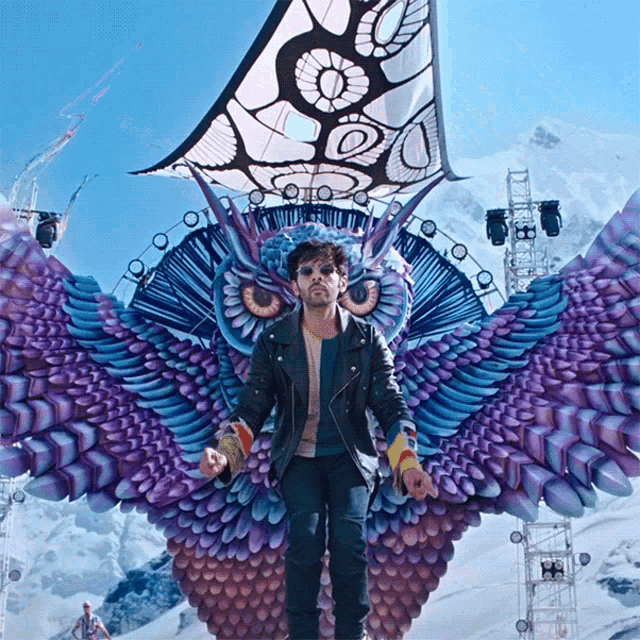 a man is standing in front of a large owl statue
