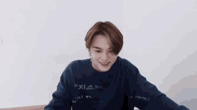 a young man wearing a blue sweater with korean writing on it