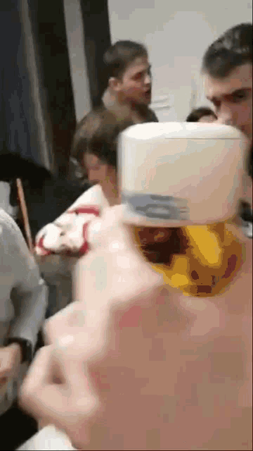 a group of people are gathered in a room and a person is holding a container in their hand