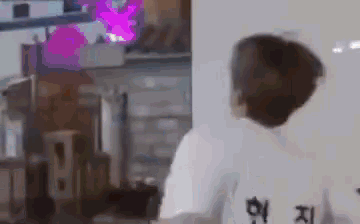 a man wearing a white shirt with chinese writing on the back is standing in front of a computer monitor .