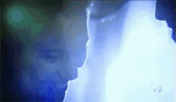 a close up of a man and woman kissing in a dark room .