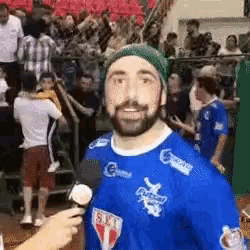 a man with a beard is wearing a blue shirt that says s.e.i. on it .