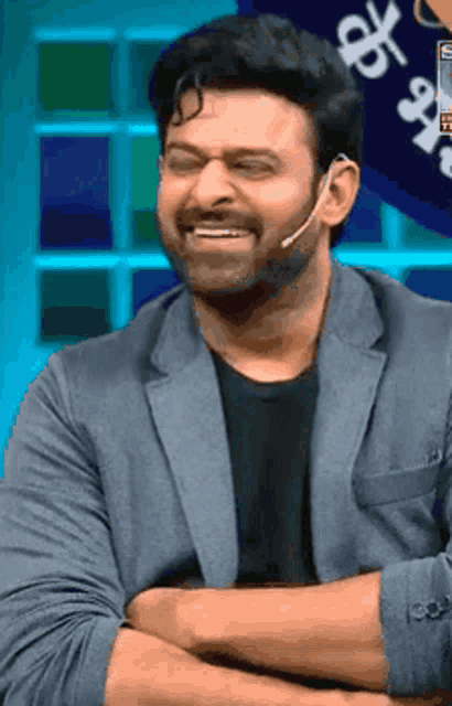 a man with a microphone in his ear is smiling with his arms crossed