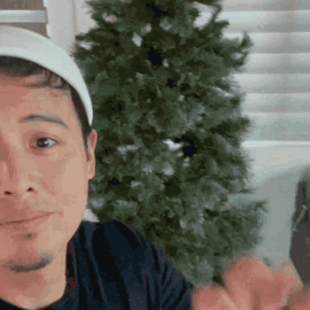 a man wearing a headband looks at the camera with a christmas tree in the background
