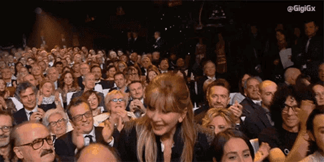 a crowd of people applauding with the hashtag gigigx in the corner