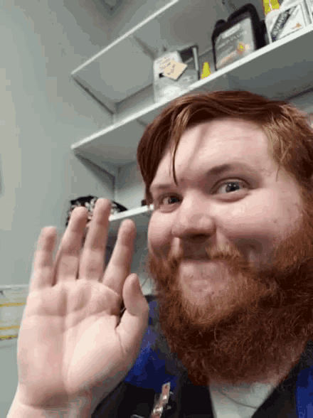 a man with a beard is giving a high five in front of a shelf with a bottle of kleenex on it
