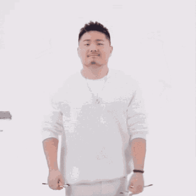 a man with a beard is wearing a white shirt and holding a pair of brushes .