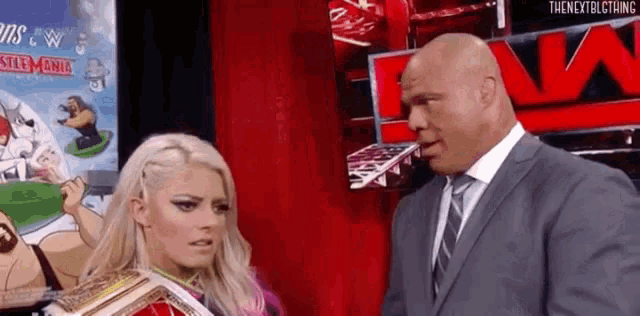 a man in a suit and tie is standing next to a woman in a ring holding a trophy .