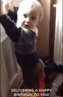 a little boy is standing in front of a door and making a face .