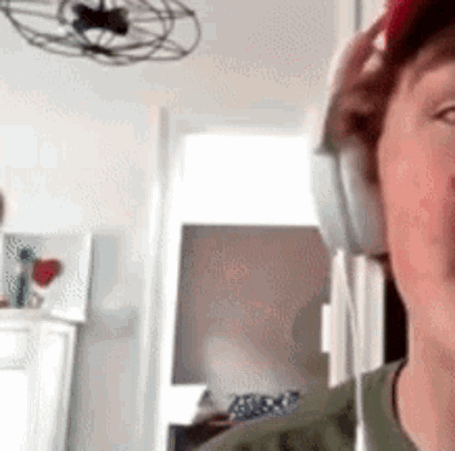 a man wearing headphones and a red hat is standing in a room .