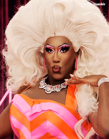 a drag queen is wearing a pink and orange striped dress and a large white wig