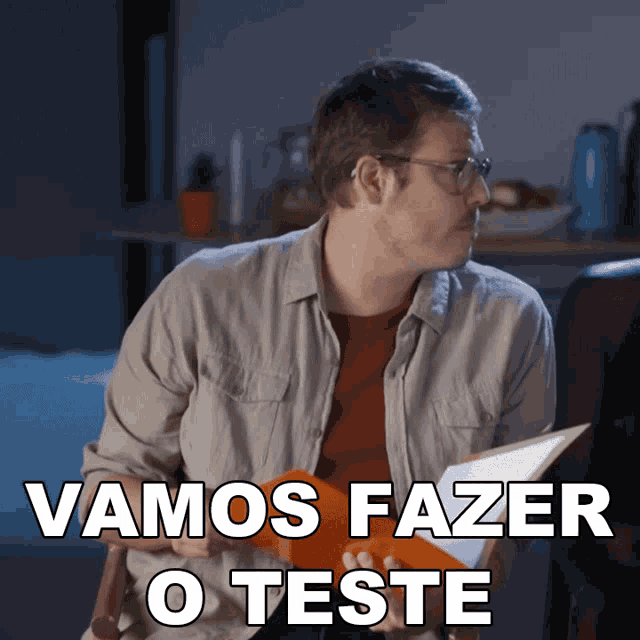 a man with glasses holds a piece of paper that says " vamos fazer o teste "