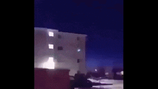 a blurry picture of a building with a green light coming out of the window .