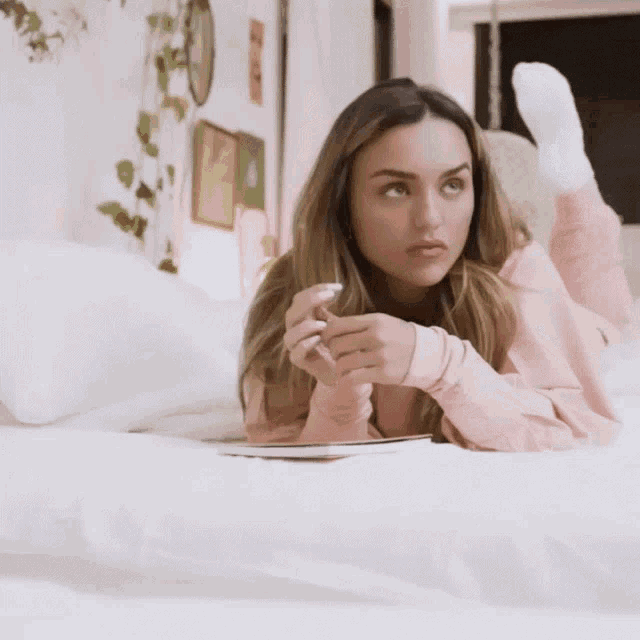a woman is laying on her stomach on a bed with her feet up