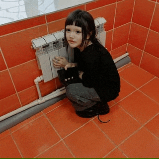 a little girl is squatting next to a radiator