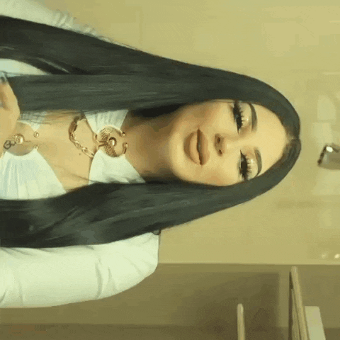a woman with long black hair wearing a white shirt and a necklace .