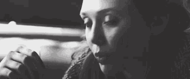 it is a black and white photo of a woman smoking a cigarette .