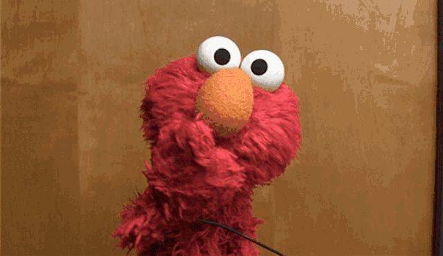 elmo from sesame street looks at the camera with his mouth open