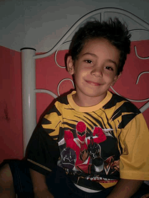 a young boy wearing a power rangers shirt is smiling