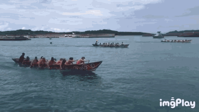 a group of people are rowing a boat in the ocean with a watermark that says imgplay on the bottom