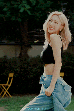 a woman in a black tank top and blue jeans is smiling for the camera