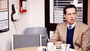 a man in a suit and tie is sitting at a table with coffee cups .