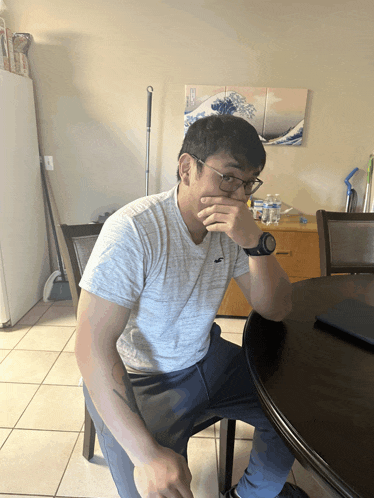 a man in a hollister shirt sits at a table with his hand over his mouth