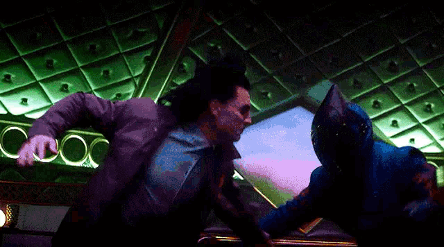 a man in a suit is fighting another man in a blue costume .