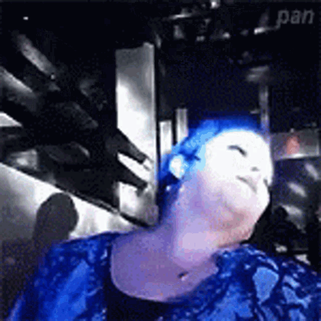 a woman with blue hair is wearing a blue shirt and a black top .