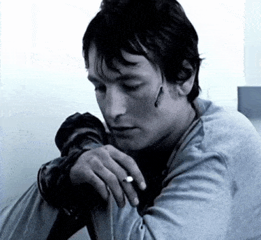 a man wearing a ring on his finger is smoking a cigarette