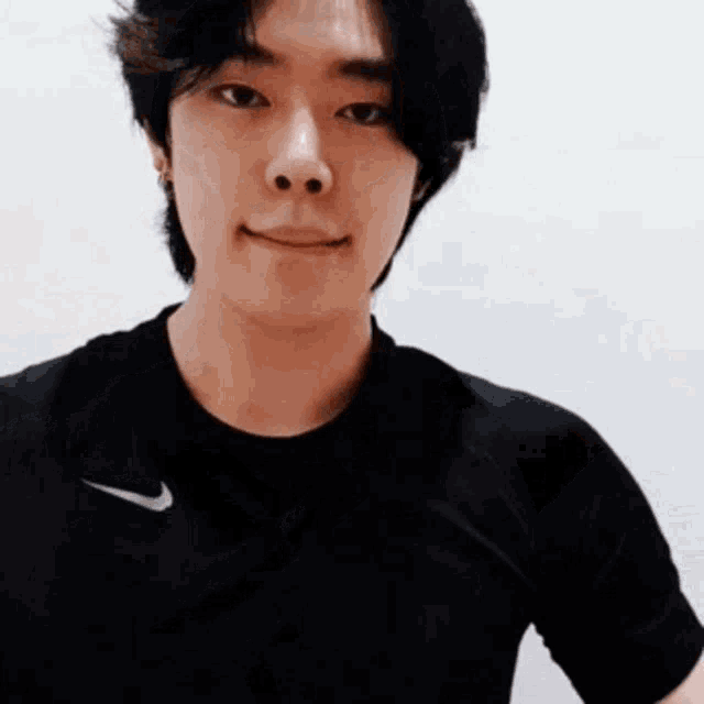 a young man wearing a black nike t-shirt is smiling .