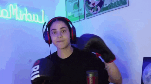 a young woman wearing headphones and boxing gloves is standing in front of a microphone .