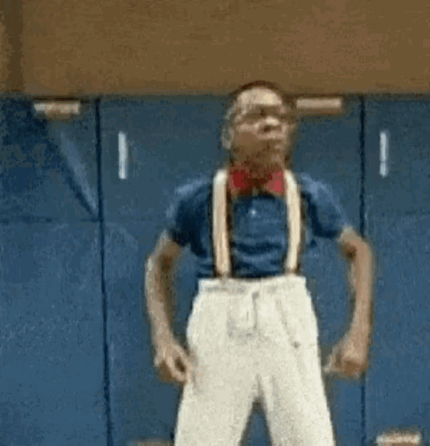 a man wearing suspenders and glasses is standing in a gym .