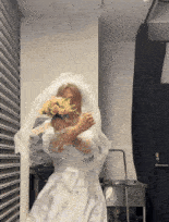 a woman in a wedding dress holds a bouquet of flowers in front of her face
