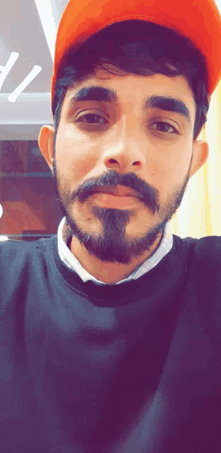 a man with a beard wearing an orange hat and a black shirt