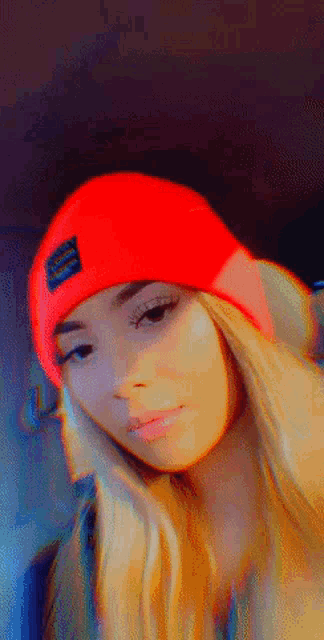 a woman wearing a red beanie with the word supreme on the front