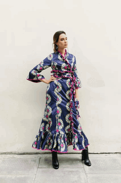 a woman wearing a blue dress with flowers on it is standing on a sidewalk