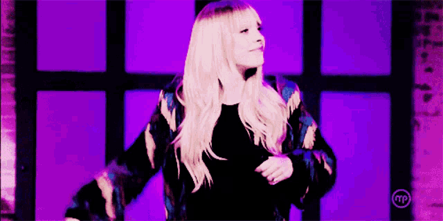a woman is dancing in front of a purple background with a tp logo on it