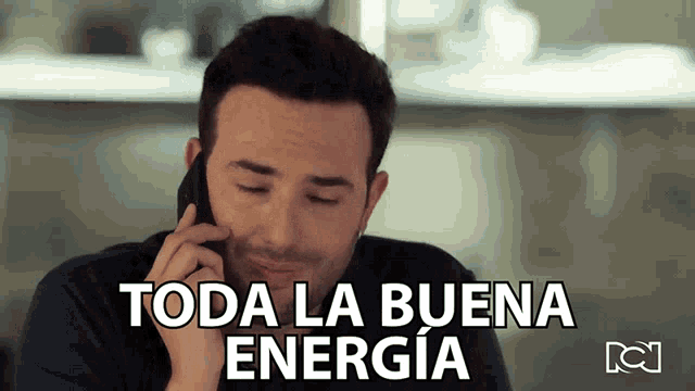 a man is talking on a cell phone and the words toda la buena energia are above him