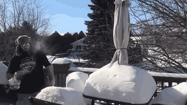 a man wearing a shirt that says brew the moon is standing on a snowy deck