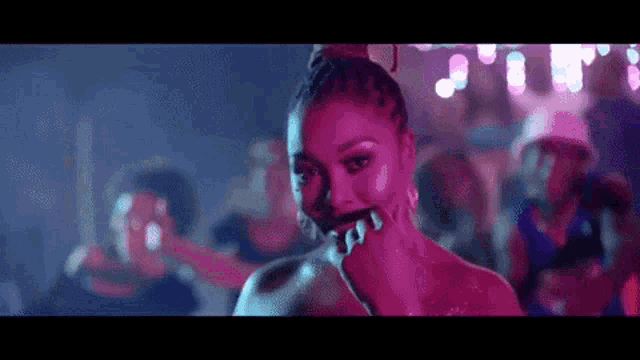 a woman is dancing in a club with a group of people behind her .